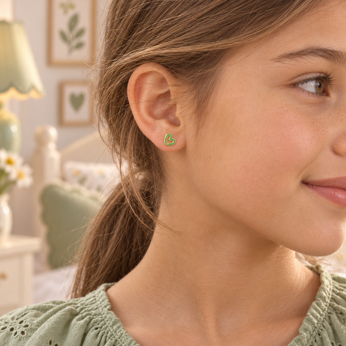 Mint green heart hypoallergenic earring worn in a child’s ear, designed for sensitive ears