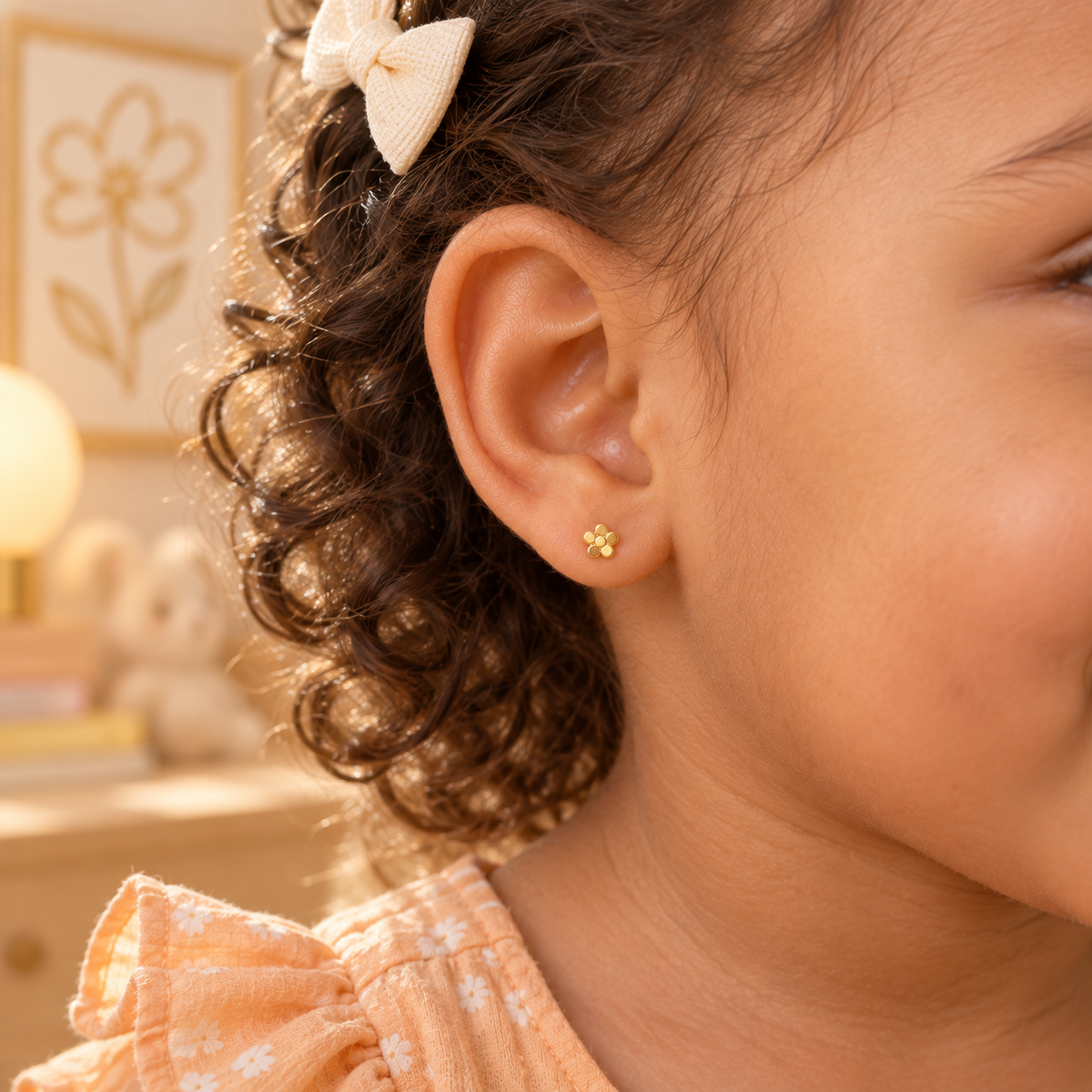 Tiny gold flower hypoallergenic earring worn in a child’s ear, designed for sensitive ears
